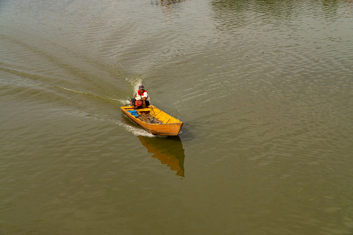 The fisherman is on a boat sailing on the lake