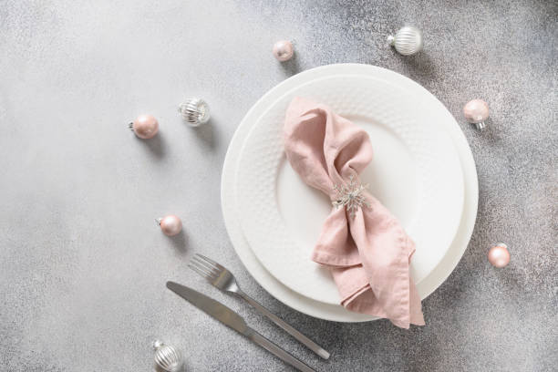 Christmas festive table setting with pink ball and napkin on gray table.