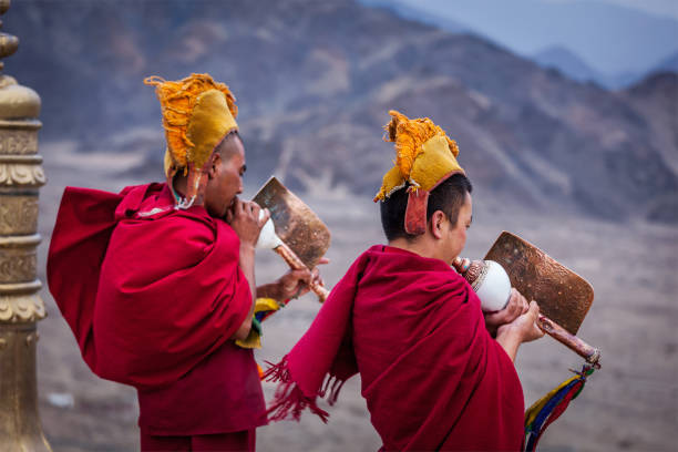 Thiksey, India - September 4, 2011: Two Tibetan Buddhist monks blowing conches during morning pooja, Thiksey gompa, Ladakh, India