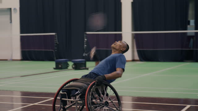 Asian male disability in an blue sportswear sits in a competitive wheelchair warm up on a court.