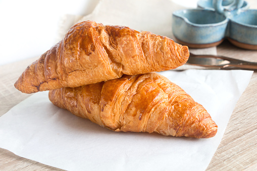 Two french croissant on the grey wooden table decorated with napkin.
