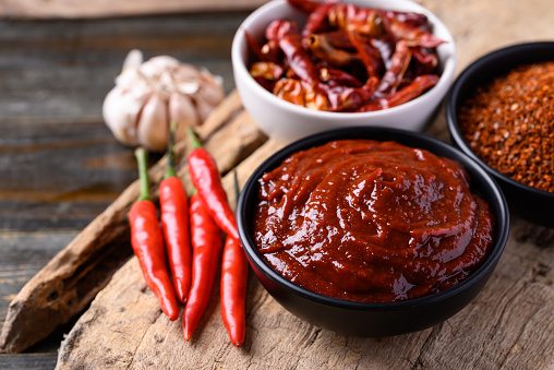 Gochujang (red chili paste) in bowl on wooden background, spicy and sweet fermented condiment in Korean food