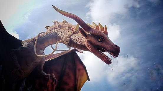 Close Up of Head of mythological animal dragon against blue cloudy sky background
