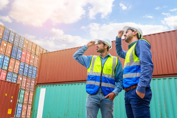 istock Professional of two Engineers or foreman container cargo wearing white hardhat and safety vests checking stock into container for loading from Cargo freight ship for import export. industry worker of logistic concept 1447050110