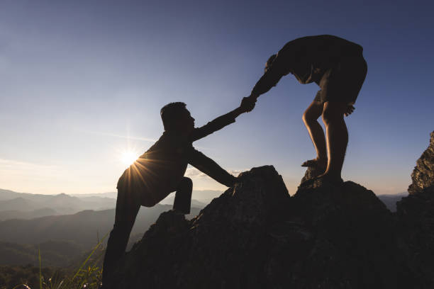 istock Silhouette of The men helping pull people up from high cliffs. 1447053190