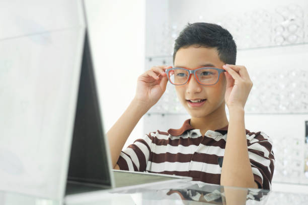 smart young boy trying out new eyeglasses. - eye exam child optometrist human eye imagens e fotografias de stock