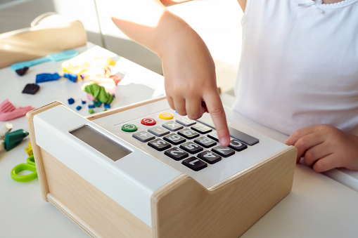 Close up of kid's finger is pressing to open the cash drawer toys in the play area. The concept of financial literacy of children. High quality horizontal white photo