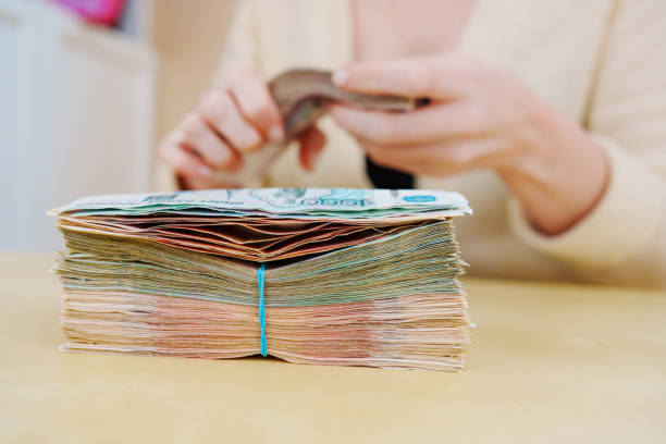 istock women's hands hold a stack of rubles tied with a rubber band. 1447057751