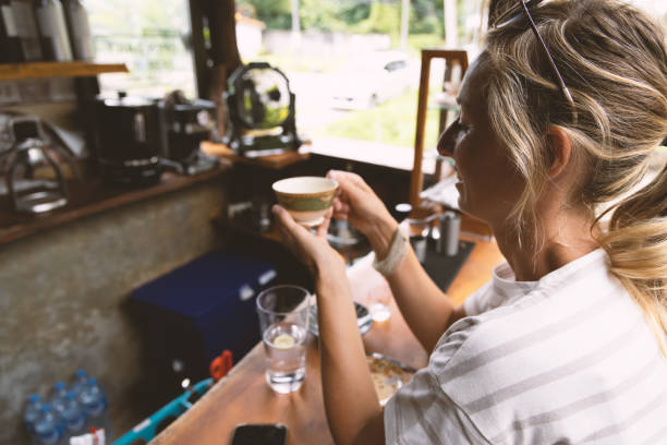 młoda kobieta pijąca kawę w lokalnej kawiarni w azji, doświadczalna podróż z różnorodnością - caffeine caucasian satisfaction small business zdjęcia i obrazy z banku zdjęć