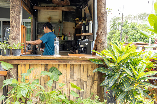 Thai owner working in his small coffee shop, he is making an espresso using a handmade coffee machine. Small business concept