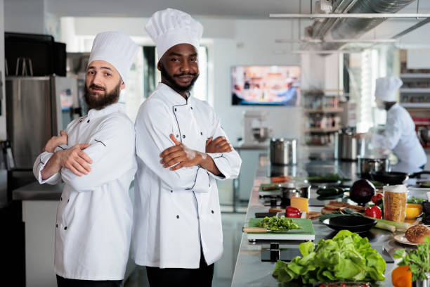 istock Multiethnic male cooks standing in restaurant professional kitchen with arms crossed while preparing ingredients for dish. 1447066167