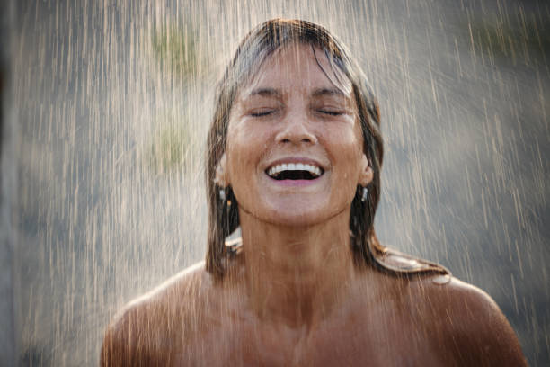 istock Happy woman with closed eyes under falling water. 1447070035