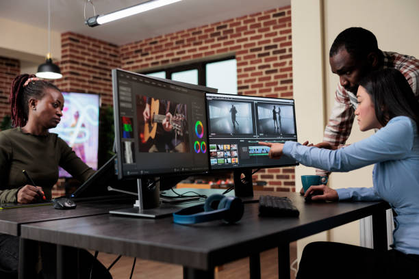 istock Professional videographer sitting at desk while coworker helping her with film footage visual quality improvement. 1447070339