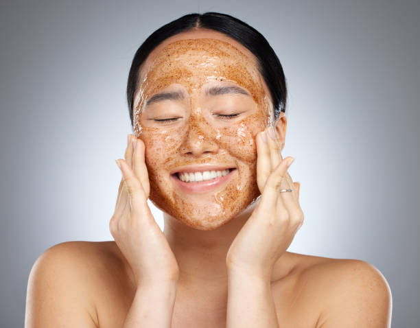 facial, product and woman skincare face mask cosmetics cleaning smooth and soft skin in asian studio. relaxed, smile and happy beauty model peeling a healthy natural grooming scrub or mud in seoul - lipstick make up cosmetics grooming product imagens e fotografias de stock