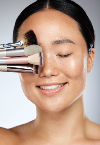 istock Makeup, beauty and Asian woman with brushes in studio for cosmetics design. Creative, cosmetology and happy girl with different makeup brushes on natural face for fashion, style and beauty products 1447071724