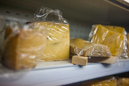 A closeup of cheese in the plastic packaging on the shelf.
