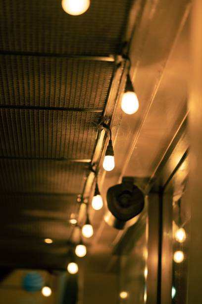 istock Vertical shot of lit light bulbs hanging from a building 1447074002
