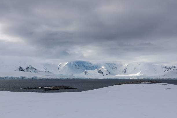 istock Snow-covered landscape of mountains range on a glacier under a grey cloudscape in Antarctica 1447074076