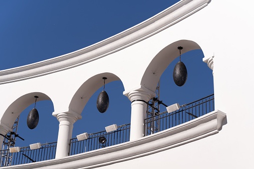 The exterior of a white building with black lamps over a background of a blue sky