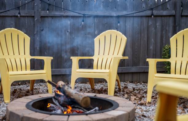 istock Fire pit with fire-burning logs, surrounded by yellow plastic chairs, in the backyard 1447076861