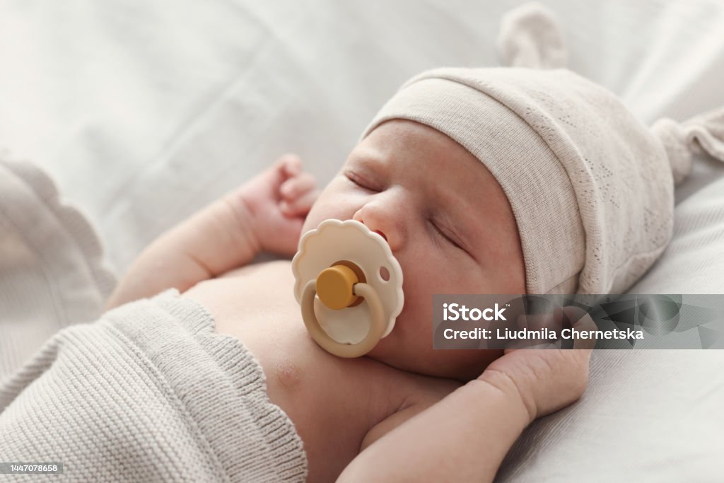 Adorable little baby with pacifier sleeping in bed, closeup Newborn Stock Photo