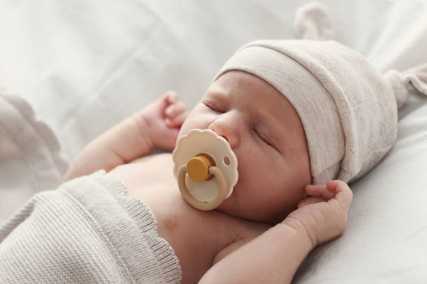Adorable little baby with pacifier sleeping in bed, closeup stock photo