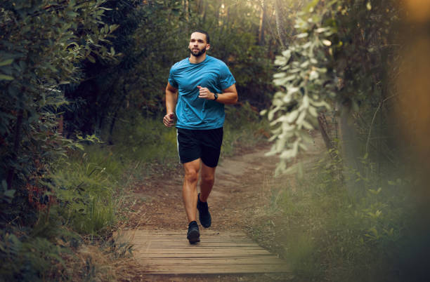 fitness, uomo e corsa nella natura per un sano esercizio fisico, allenamento e allenamento all'aria aperta. corridore maschio attivo e atletico nello sport che fa jogging nella foresta o nel parco per la salute e il benessere cardio - endurance sport foto e immagini stock