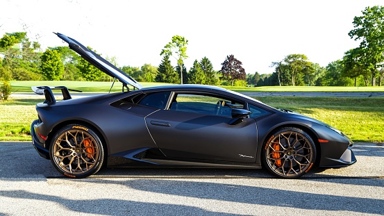 Milwaukee, United States – February 05, 1979: A black Lamborghini Huracan from the side with an open trunk parked in the road next to a park