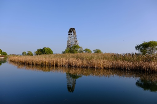 A landscape of a lake shore with a Ferris wheel carousel in the background