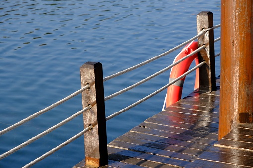 A wooden pier at the lake shore with a lifebuoy