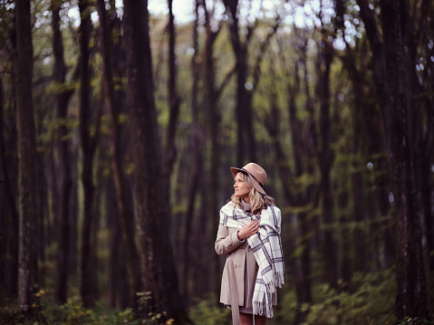 Young woman day dreaming while walking in autumn day at the forest. Copy space.