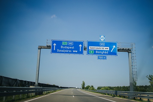A blue road sign showing the direction to Budapest over a asphalted road, Hungary