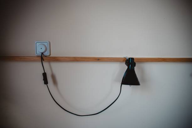 istock Modern minimalistic wall lamp hanging on a white wall and lighting in a dark room 1447084109