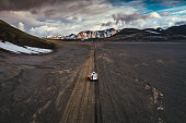 Road trip with tourist 4x4 vehicle car parked on volcanic desert with crater on dirt road in Landmannalaugar at Icelandic Highlands