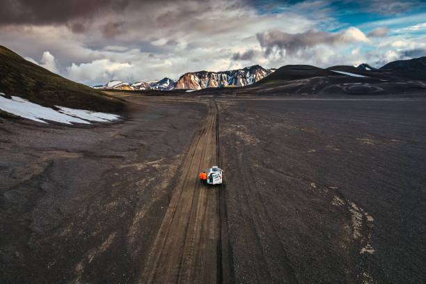 Road trip with tourist 4x4 vehicle car parked on volcanic desert with crater on dirt road in Landmannalaugar at Icelandic Highlands Aerial view of Road trip with tourist 4x4 vehicle car parked on volcanic desert with crater on dirt road in Landmannalaugar at Icelandic Highlands lava a car a stock pictures, royalty-free photos & images