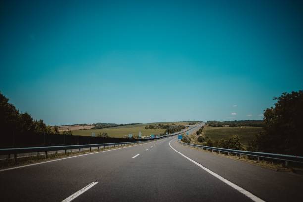 istock Long asphalt road through a rural field under a blue sky 1447084292