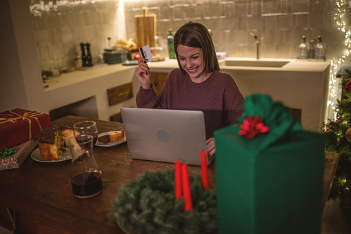 Photo of a young woman buying presents online for a Christmas holiday