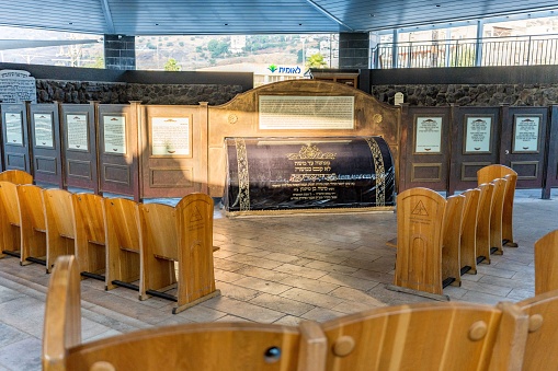 Tiberias, Israel – June 22, 2022: An inside view of the tomb of Maimonides with wooden chairs and a wooden board with writings,Tiberias, Israel