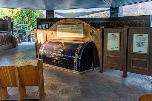 Tiberias, Israel – June 22, 2022: An inside view of the tomb of Maimonides with wooden chairs and a wooden board with writings,Tiberias, Israel