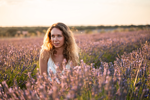 Beauty blonde woman in a lavender field during sunset