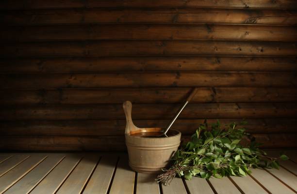 A birch bath whisk (vihta) and a water pail ready for bathers in a Finnish sauna.  Room for copy.
