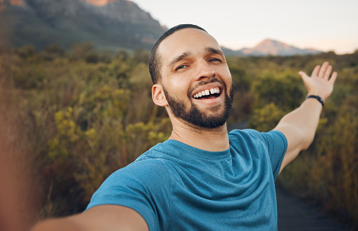 Happy, nature and man taking a selfie in the countryside for a peaceful holiday adventure outdoors in spring with freedom. Smile, pictures and man enjoying traveling and quality vacation time alone