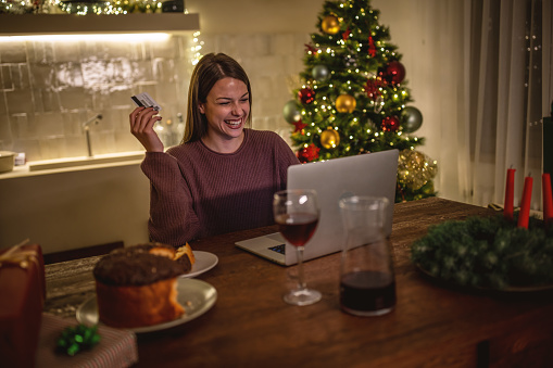 Photo of a young woman buying presents online for a Christmas holiday