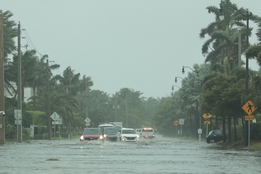 A flooded road with cars passing through during hurricane Nicole in Palm Beach, Florida. November 2022