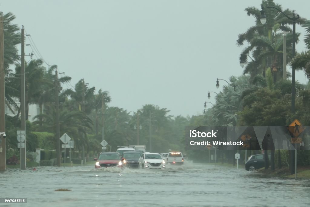 Flooded road with cars passing through during hurricane Nicole in Palm Beach, Florida. November 2022 A flooded road with cars passing through during hurricane Nicole in Palm Beach, Florida. November 2022 Flood Stock Photo