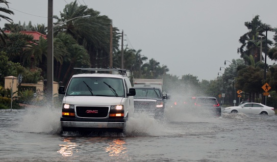 PALM BEACH, United States – November 19, 2022: A flooded road with cars passing through during hurricane Nicole in Palm Beach, Florida. November 2022