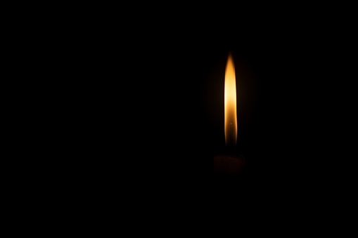 A closeup shot of an orange candle light against a black background