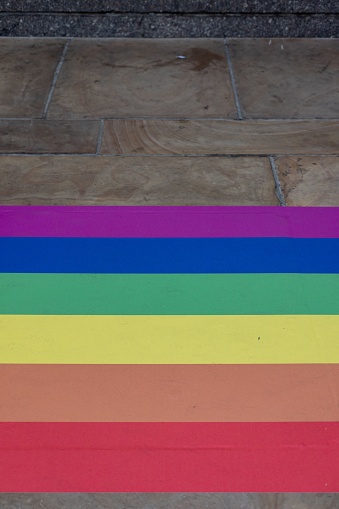 A vertical shot of a rainbow pride flag adjoining brick road