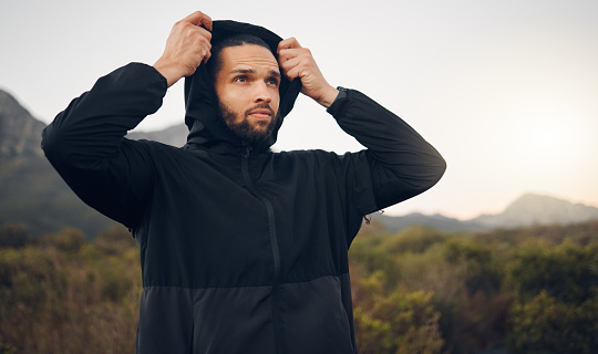 Hiking man, nature and morning fitness for freedom, running and exercise in mountains, adventure and wellness. Focus mindset of thinking runner with hoodie for cold, calm and healthy training workout