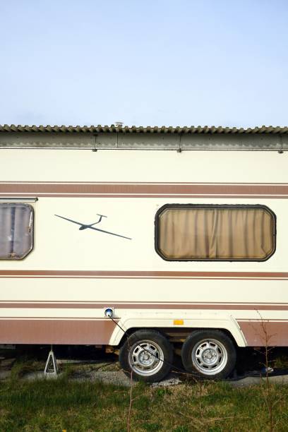 istock Vertical closeup of a light colored camper parked in a field under the sun 1447093077